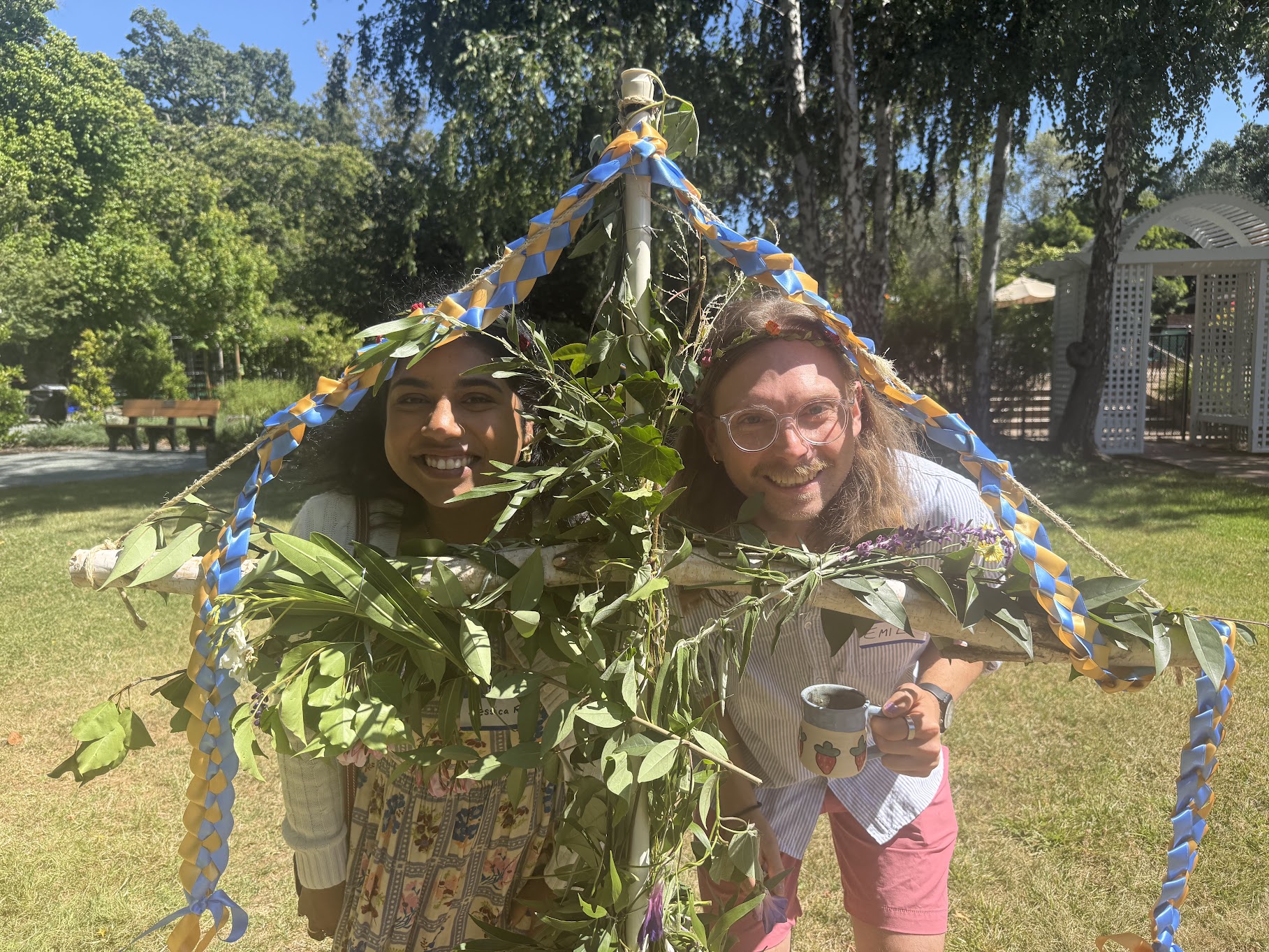 Jessica and Emil smiling beneath a leafy midsummer arch